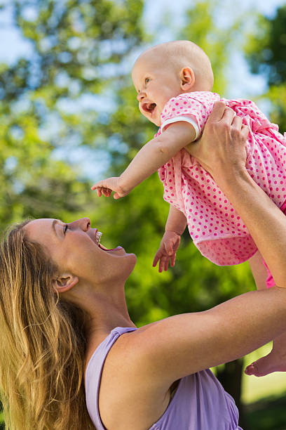 Side view of a young woman carrying cute little baby at the park